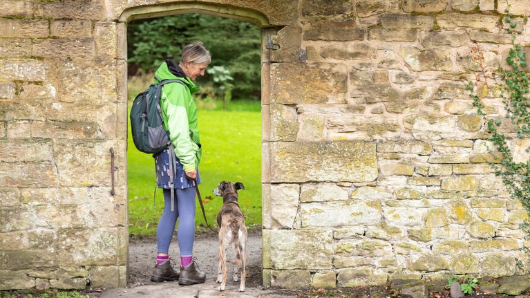 Visitor walking their dog in the garden at Gawthorpe Hall, Lancashire